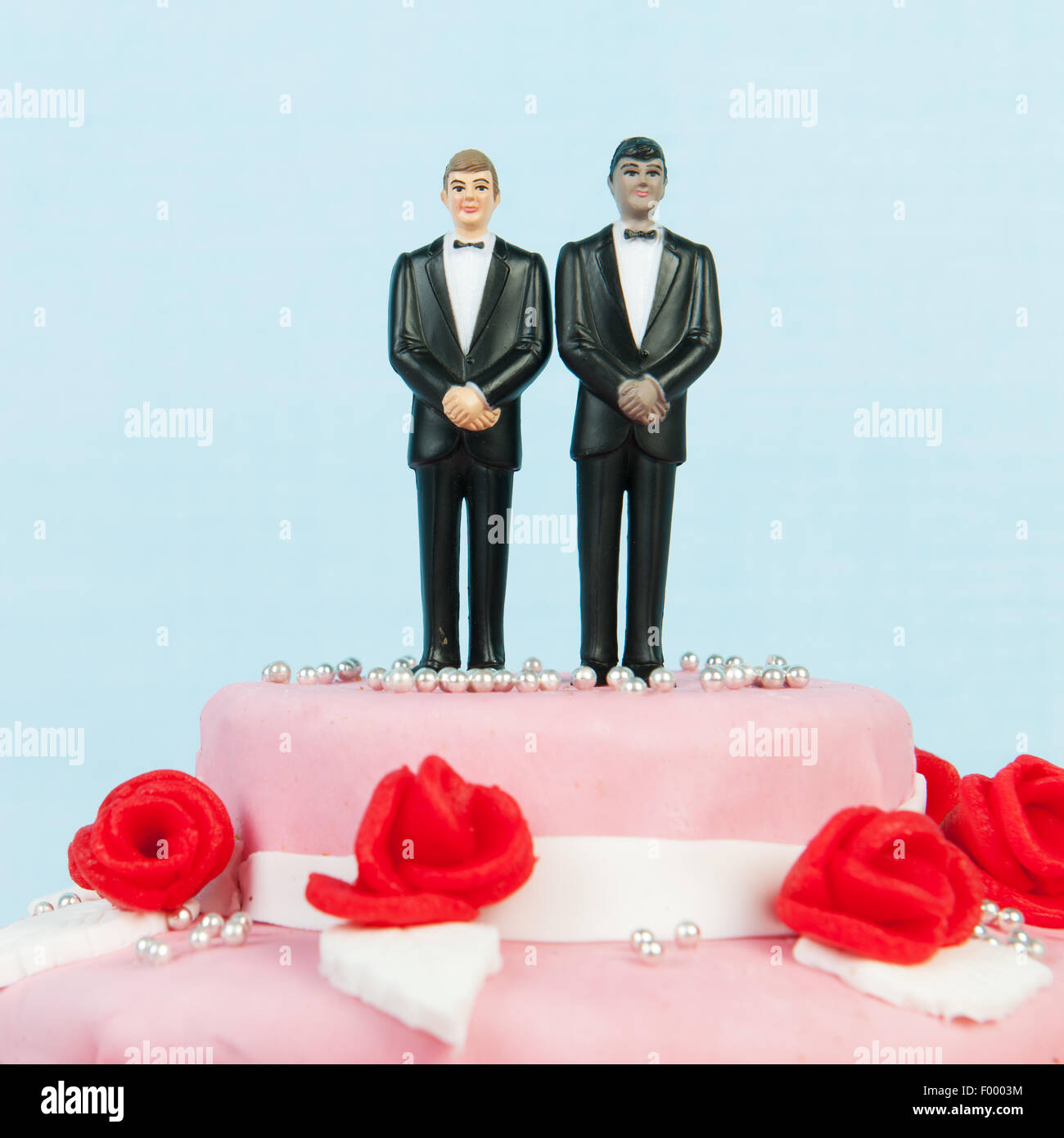 Rosa torta di nozze con rose rosse e coppia gay sulla parte superiore Foto Stock