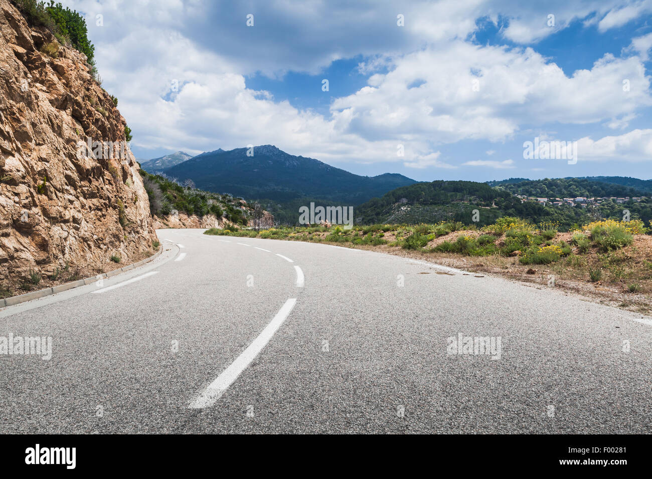 Girando su strada di montagna con una linea di demarcazione su asfalto, il paesaggio della Corsica, Francia Foto Stock