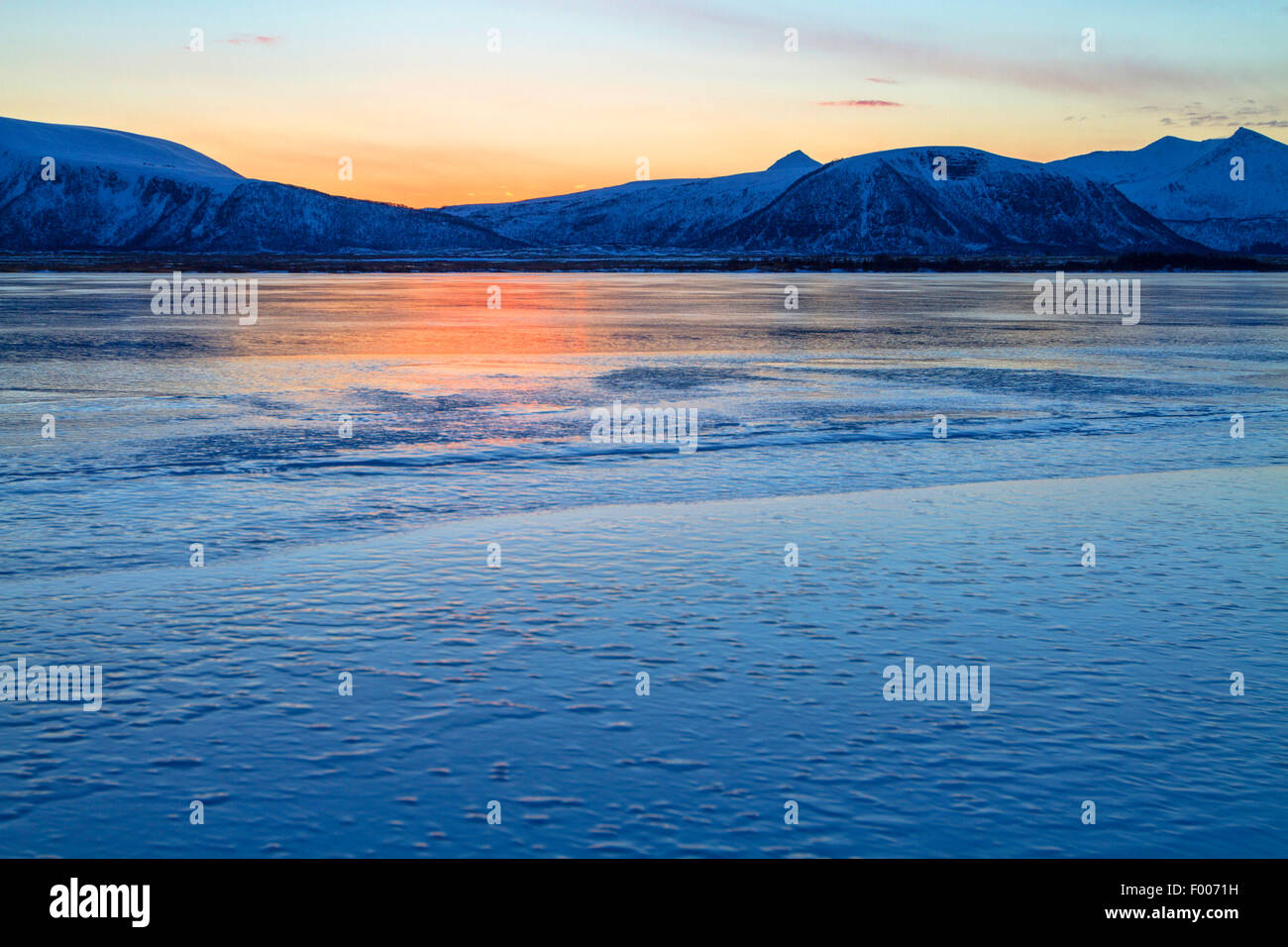 Lo splendore del sole di mezzanotte mirroring su un lago ghiacciato, Norvegia, VesterÕlen, Insel e°ya, Andenes Foto Stock