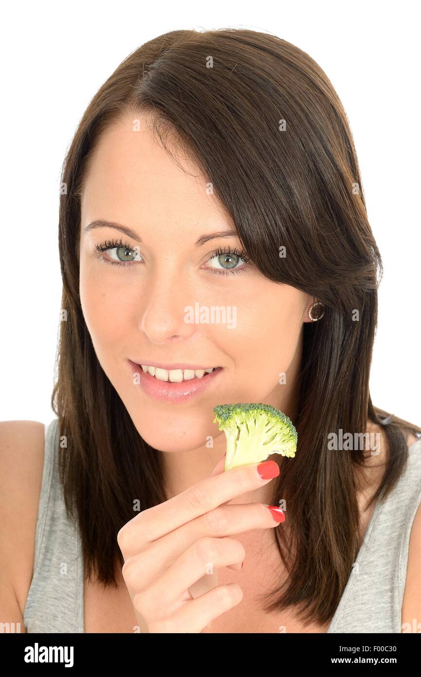 Felice positivo giovane donna mangiar sano non cotti crudo verdure broccoli isolata contro uno sfondo bianco con un tracciato di ritaglio Foto Stock