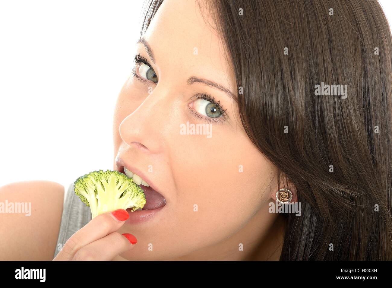 Felice positivo giovane donna mangiar sano non cotti crudo verdure broccoli isolata contro uno sfondo bianco con un tracciato di ritaglio Foto Stock