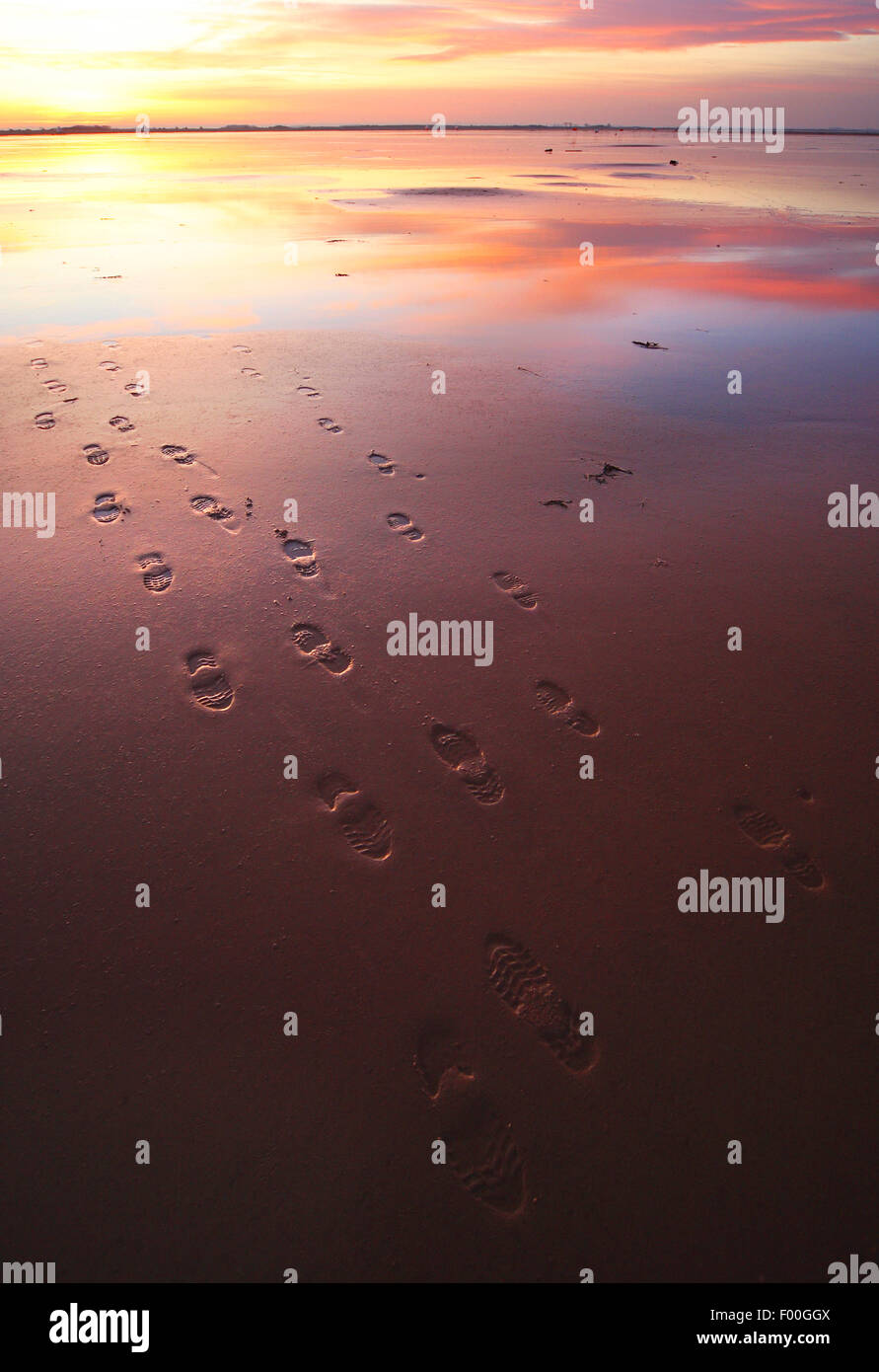 Impronte sulla spiaggia di marea in uscita e di riflessione di nuvole, velme al tramonto, Regno Unito Foto Stock