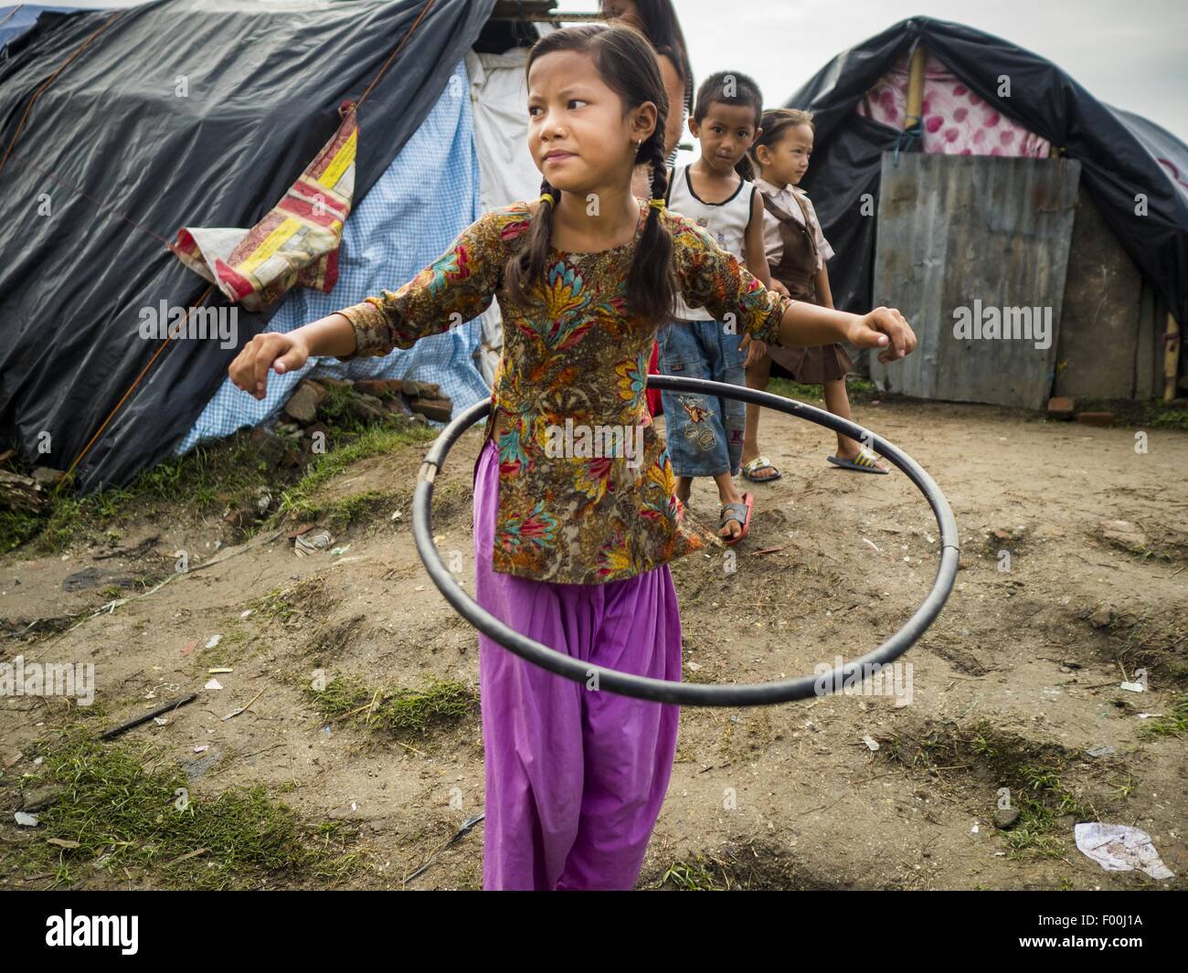 Kathmandu, Nepal. 5 Ago, 2015. Una bambina gioca con una casa fatta ''hula hoop'' tipo giocattolo in interno un grande sfollati (IDP) Camp nel centro di Kathmandu. Il camp è accanto a uno dei più costosi hotel internazionale di Kathmandu. Più di 7.100 persone sfollate dal Nepal terremoto in aprile vivono in 1.800 tende diffondere attraverso lo spazio di tre campi da calcio. Non c è elettricità in camp. Credito: ZUMA Press, Inc./Alamy Live News Foto Stock