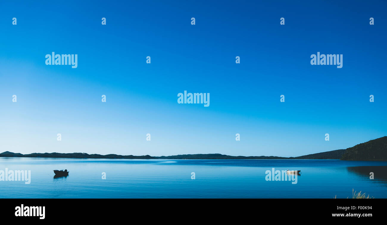 Due piccole imbarcazioni galleggianti su acqua piatta di sunrise, in ingresso Walpole Foto Stock