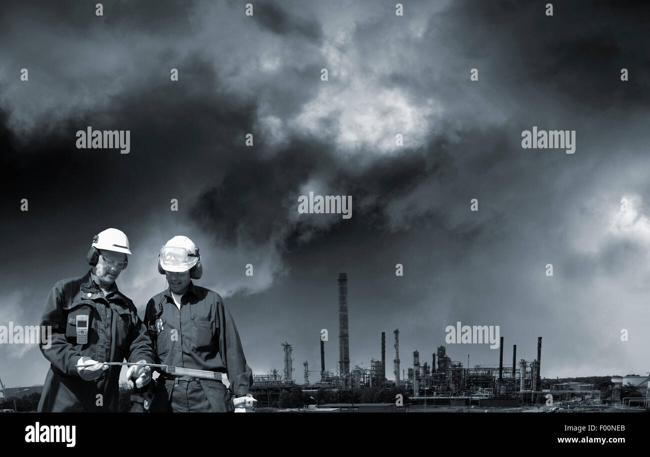 Industria della raffinazione con due lavoratori in primo piano Foto Stock