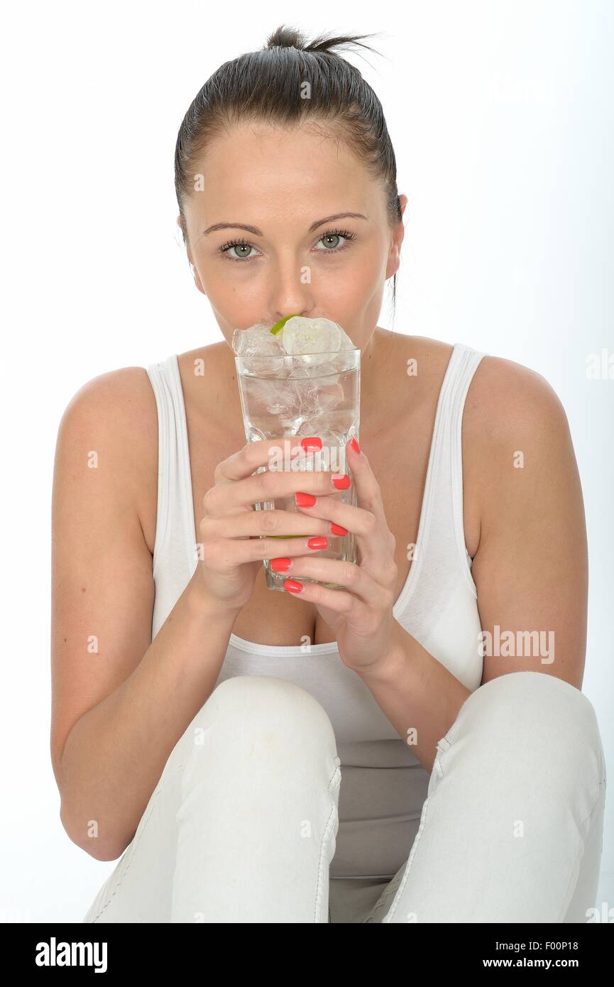 Giovane donna con in mano un bicchiere di sana ancora rinfrescante acqua ghiacciata con un segmento di calce fresca Agrumi isolata contro uno sfondo bianco Foto Stock