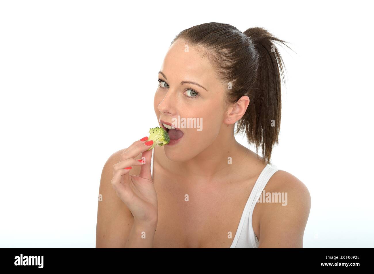 Felice positivo giovane donna mangiar sano non cotti crudo verdure broccoli isolata contro uno sfondo bianco con un tracciato di ritaglio Foto Stock