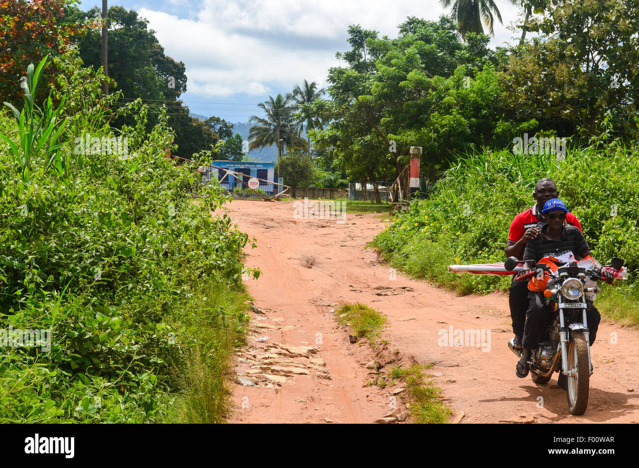 Due persone su una moto di varcare il confine tra il Ghana e il Togo in Africa occidentale, sulla strada per la città di Kpalimé Foto Stock
