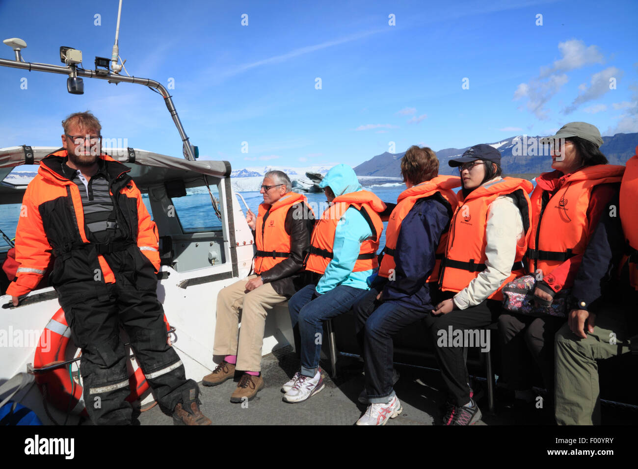 Un gruppo di passeggeri in barca arancione da indossare i giubbotti di salvataggio. Foto Stock