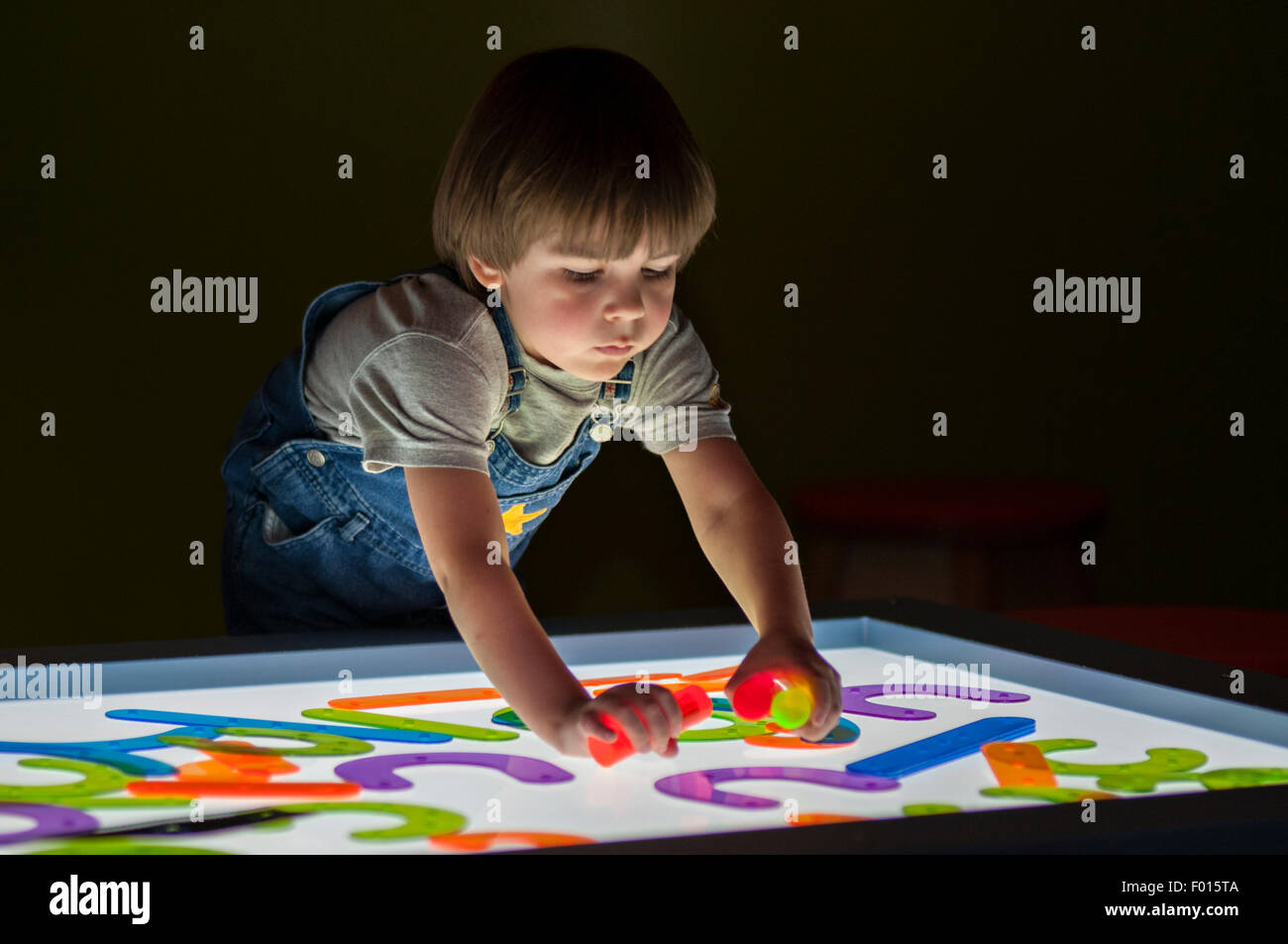 Quattro anni di vecchio ragazzo giocando con gli oggetti colorati sulla scatola di luce al Kentucky Science Center di Louisville, Kentucky Foto Stock