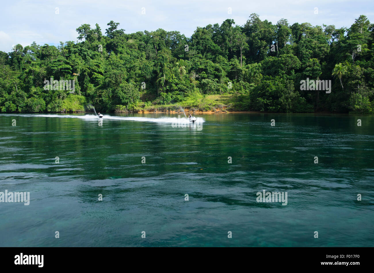 Jetskiers viaggi attraverso acqua piatta in un canale, Raja Ampat, Indonesia, Oceano Pacifico Foto Stock