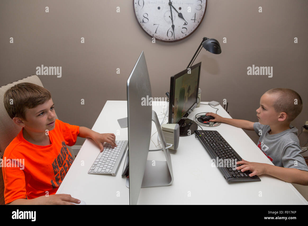 Due fratelli, nove e sette anni, riprodurre video giochi a casa dopo la scuola. Signor Foto Stock