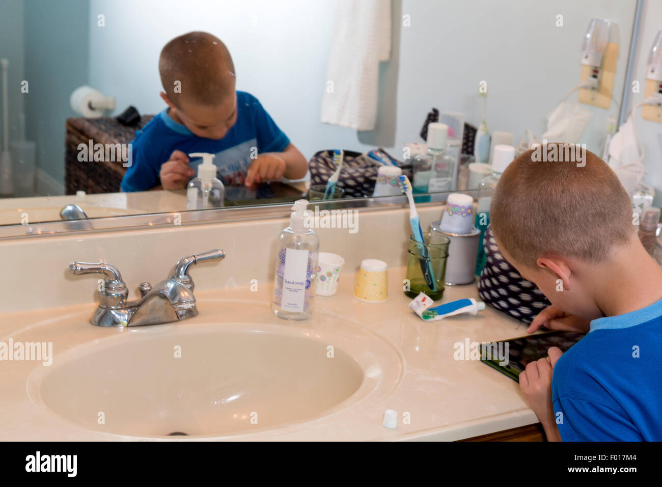 La riproduzione di videogiochi del computer rallenta sette-anno-vecchio ragazzo di spazzolare i denti a fine giornata. Signor Foto Stock