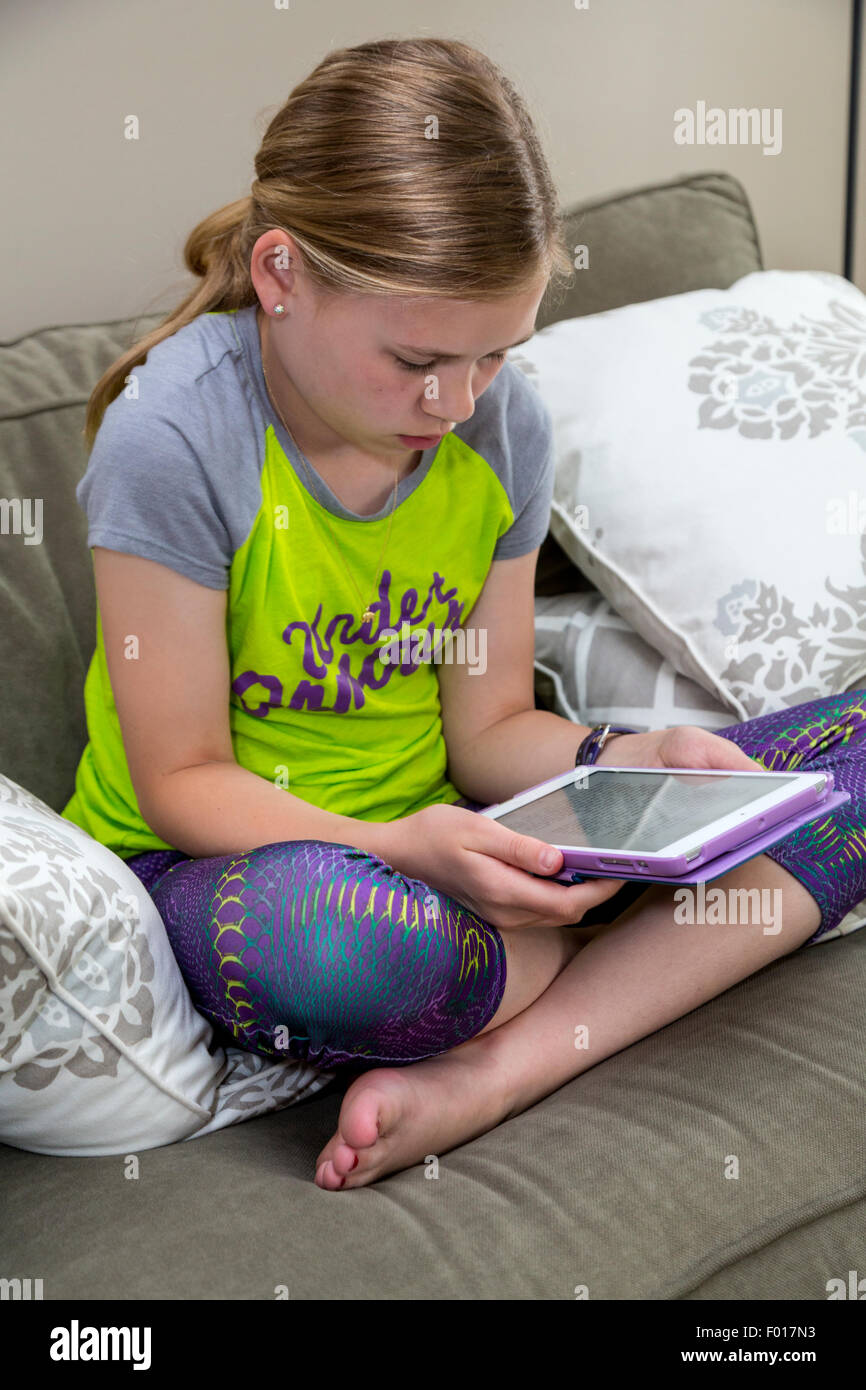 Ragazza giovane (undici anni) la lettura sul suo iPad. Signor Foto Stock
