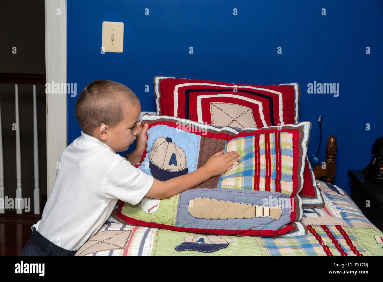 Giovane ragazzo (sette anni) rendendo il suo letto la mattina. Signor Foto Stock