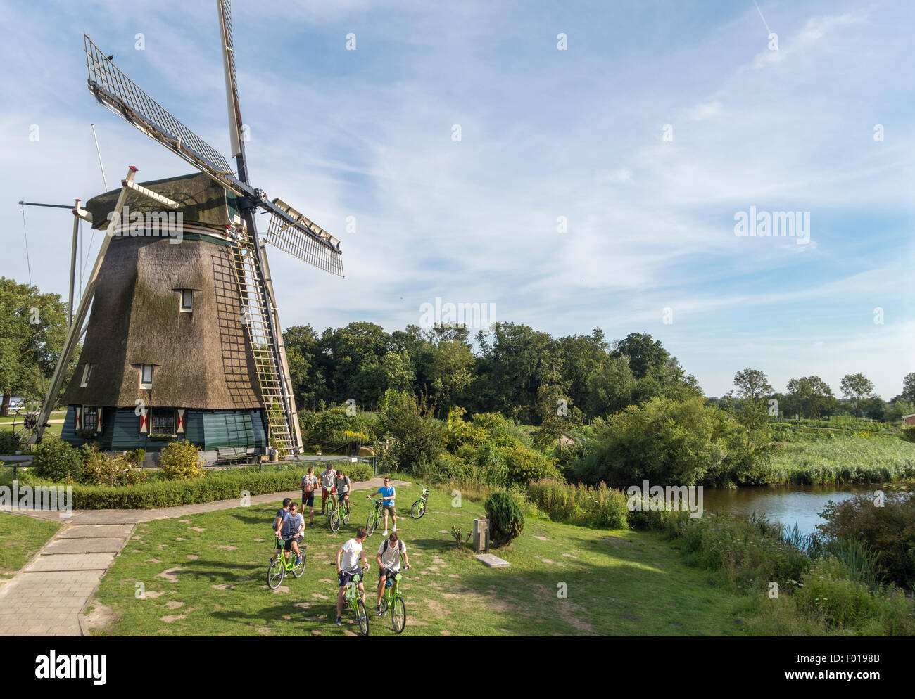 Amsterdam, il mulino a vento Rieker, de Riekermolen, sul fiume Amstel cui Rembrandt utilizzato per sketch. Giovane gruppo di tour in bicicletta. Foto Stock