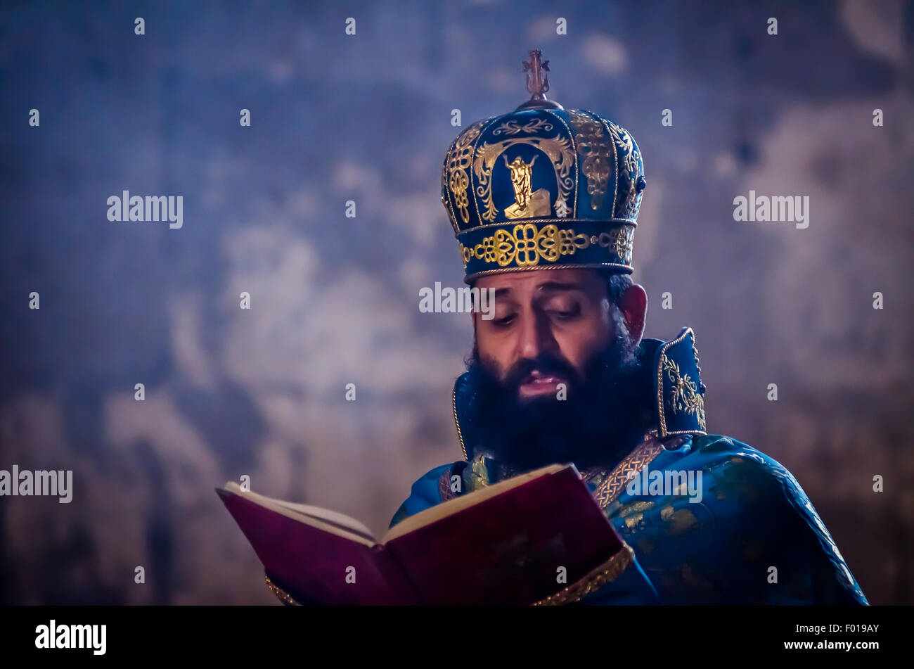 Leader spirituale che legge testo sacro in un antico ambiente scarsamente illuminato durante una tranquilla osservanza Foto Stock