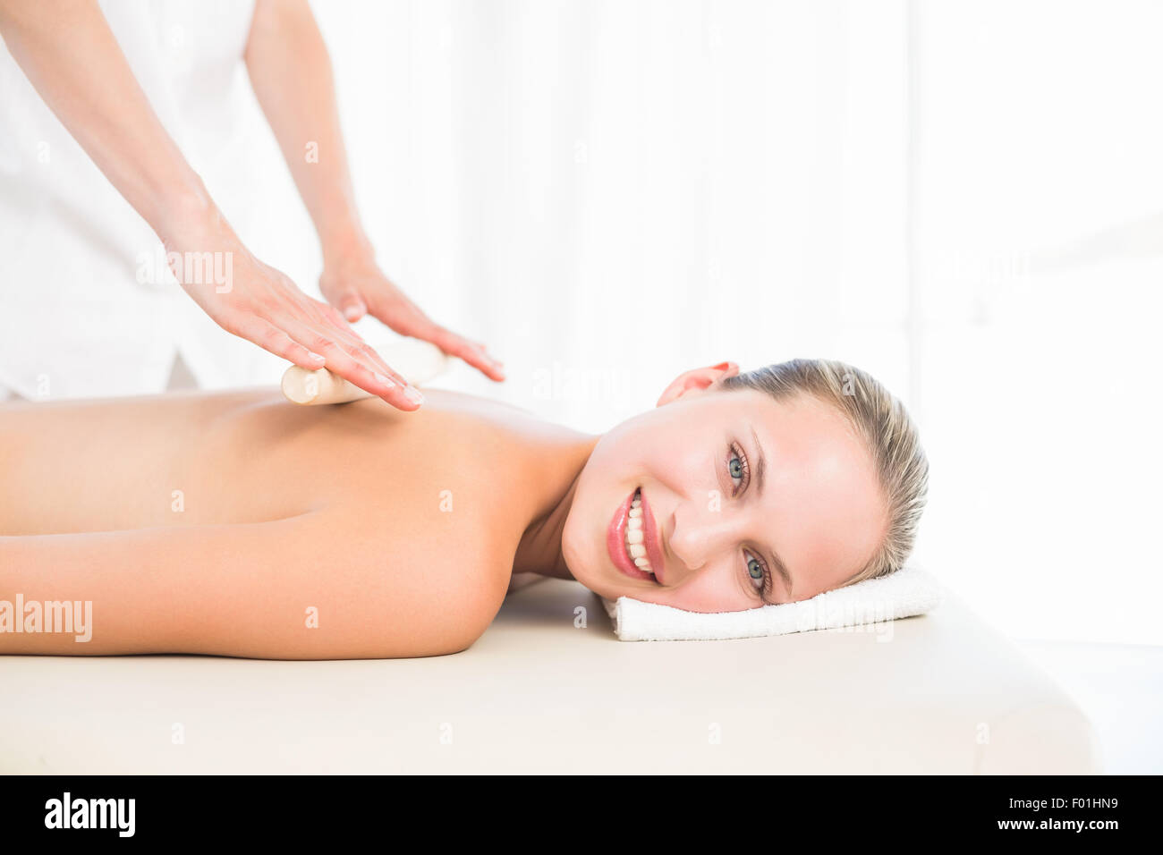 Bella bionda godendo di un rullo di bambù massaggi sorridente in telecamera Foto Stock