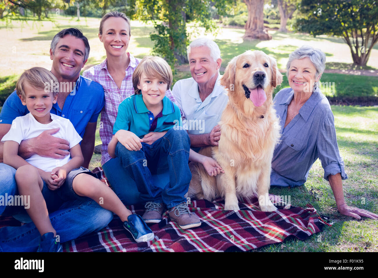 La famiglia felice sorridente verso la telecamera con il loro cane Foto Stock