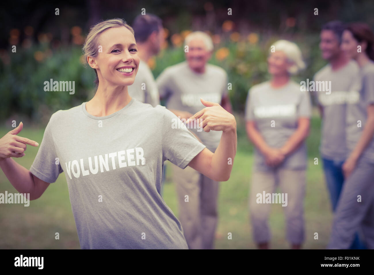 Felice volontario che mostra la sua t-shirt alla fotocamera Foto Stock