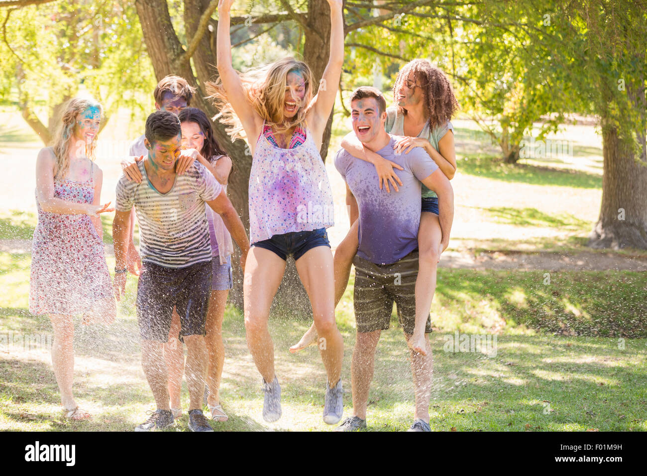 Giovani amici divertendosi con il tubo flessibile nel parco Foto Stock