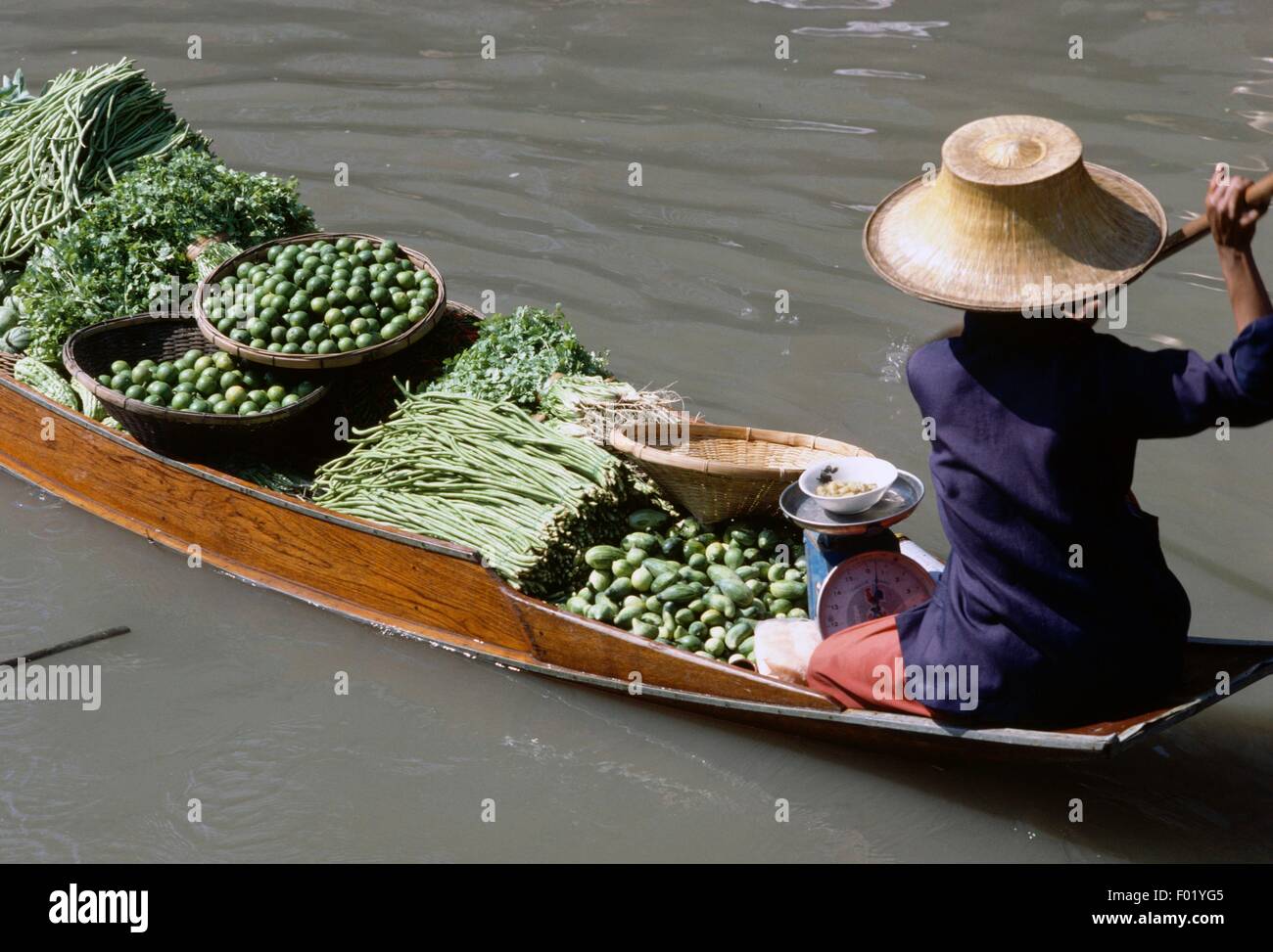 Contadino per la vendita di frutta e verdura presso un mercato galleggiante di Bangkok, Tailandia. Foto Stock
