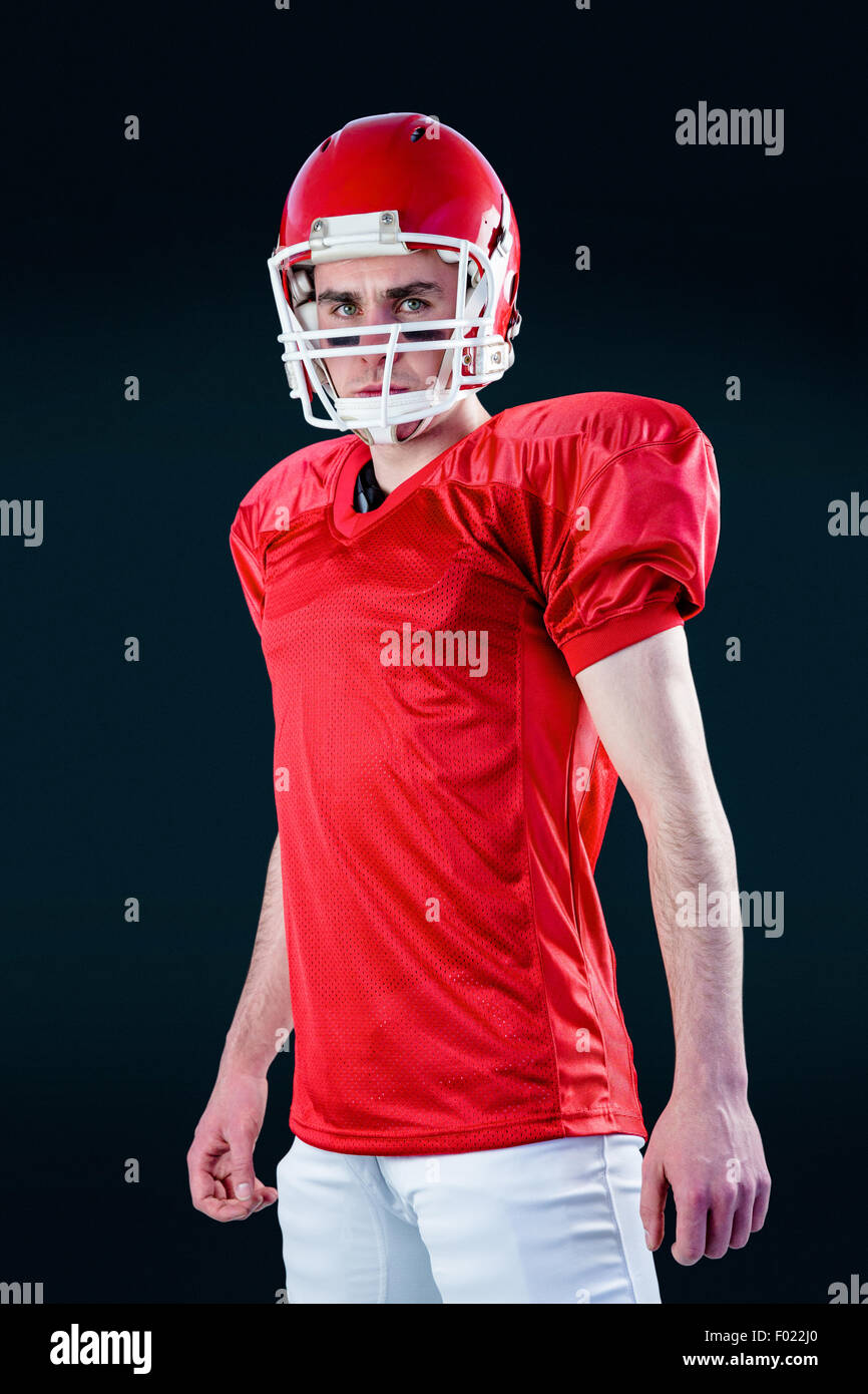 Un serio giocatore di football americano prendendo il suo casco guardando la fotocamera Foto Stock