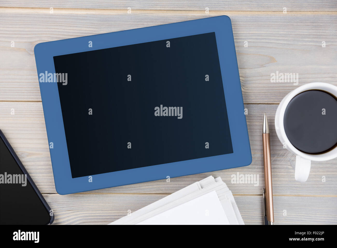 Tablet accanto alla tazza di caffè smartphone e giornale Foto Stock
