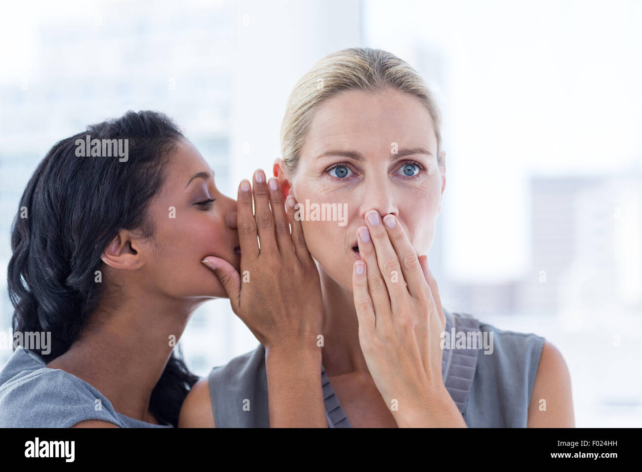 Imprenditrice whispering gossip al suo collega Foto Stock
