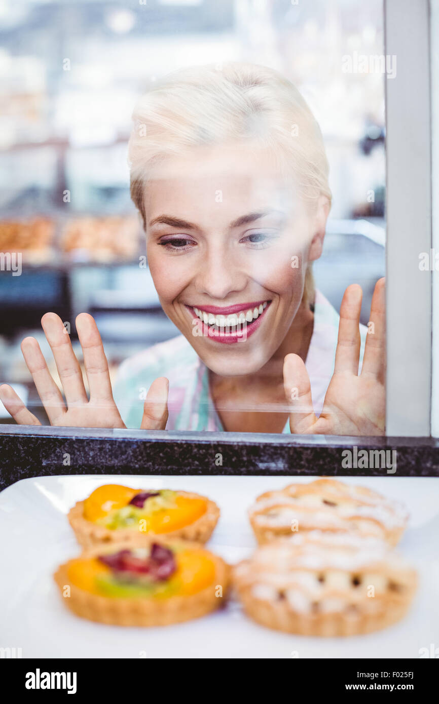 Perplesso pretty woman guardando una torta di frutta attraverso il vetro Foto Stock