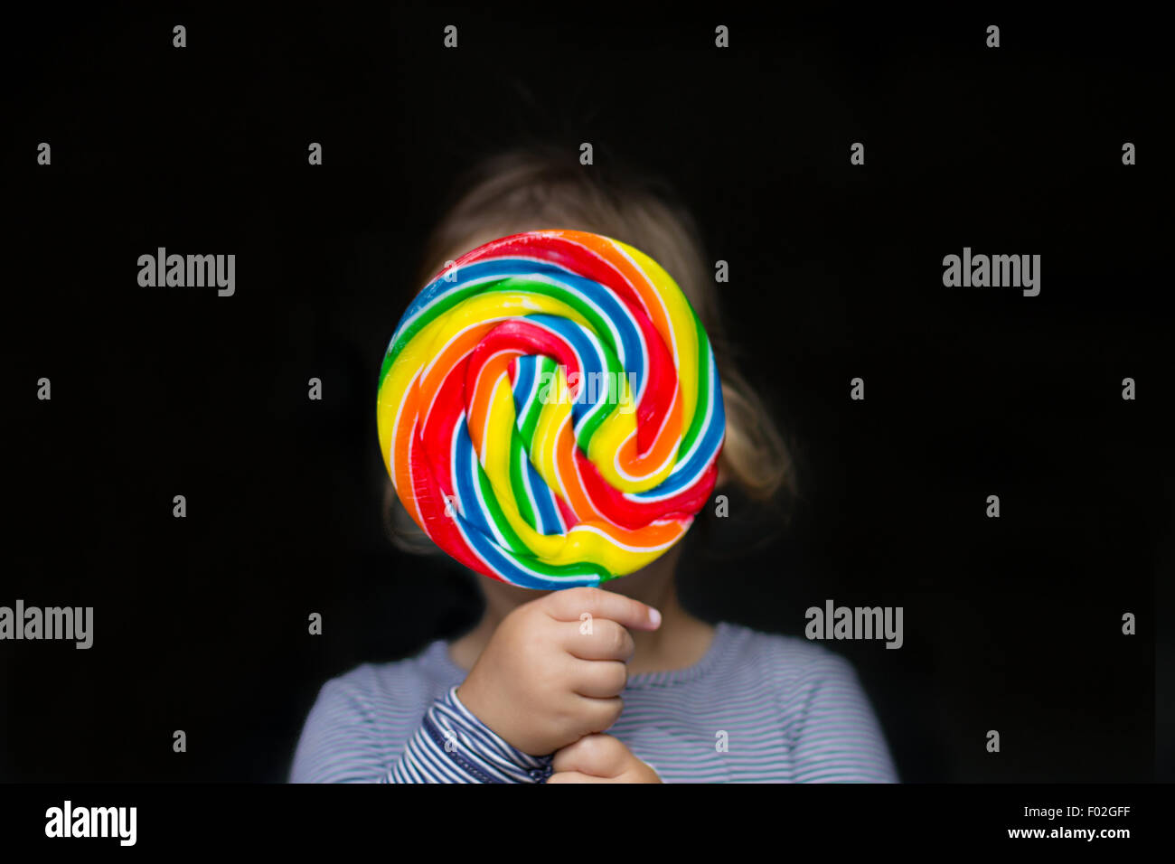 Ritratto di una ragazza che tiene un lollipop multicolore Foto Stock Ritratto di una ragazza che tiene un lollipop multicolore Foto Stock