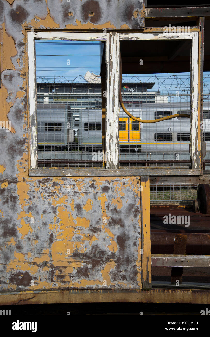 Il nuovo treno visto attraverso arrugginito, indossato capannone industriale, Sydney, Australia Foto Stock