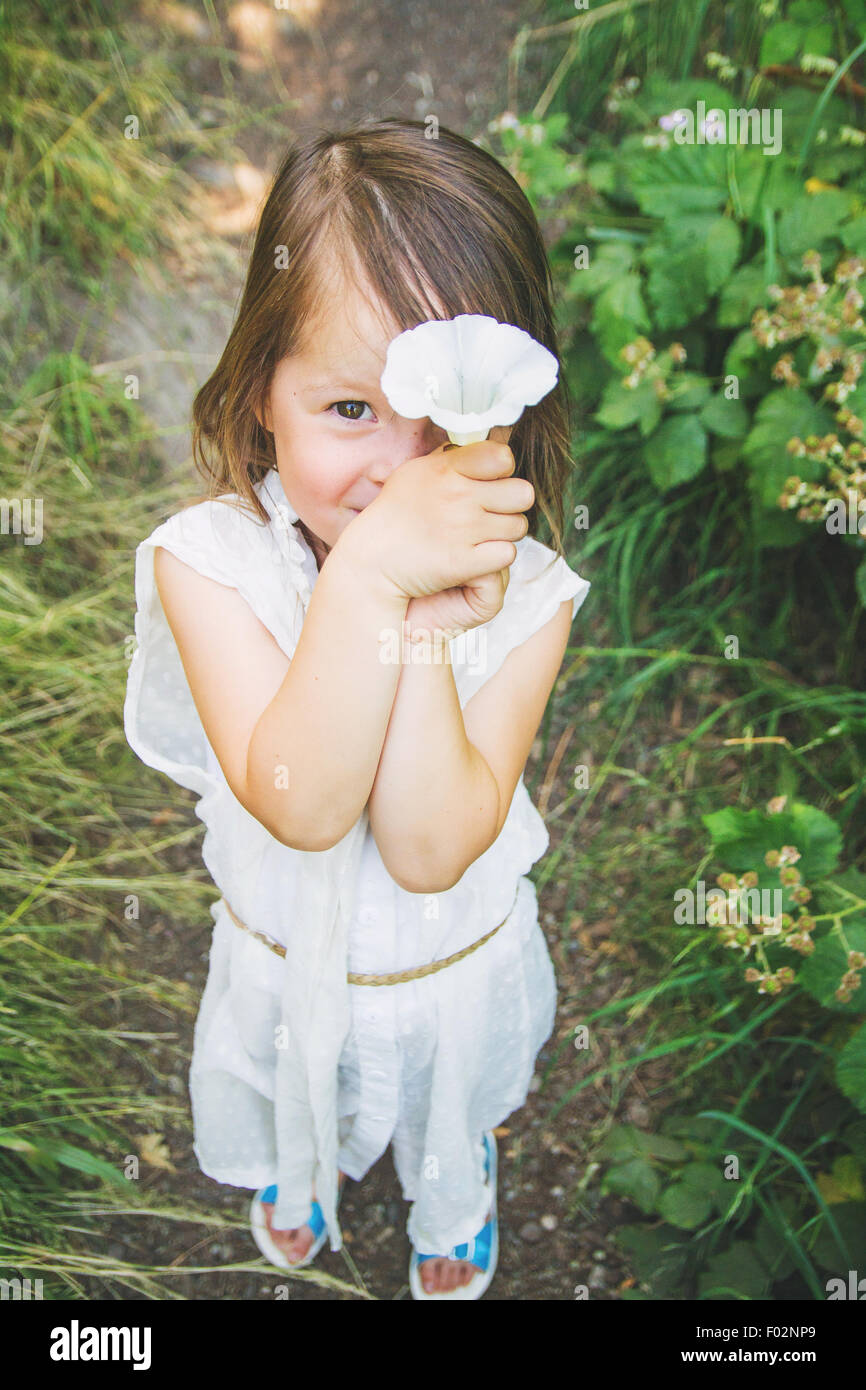 Ragazza con un fiore di fronte il suo volto Foto Stock