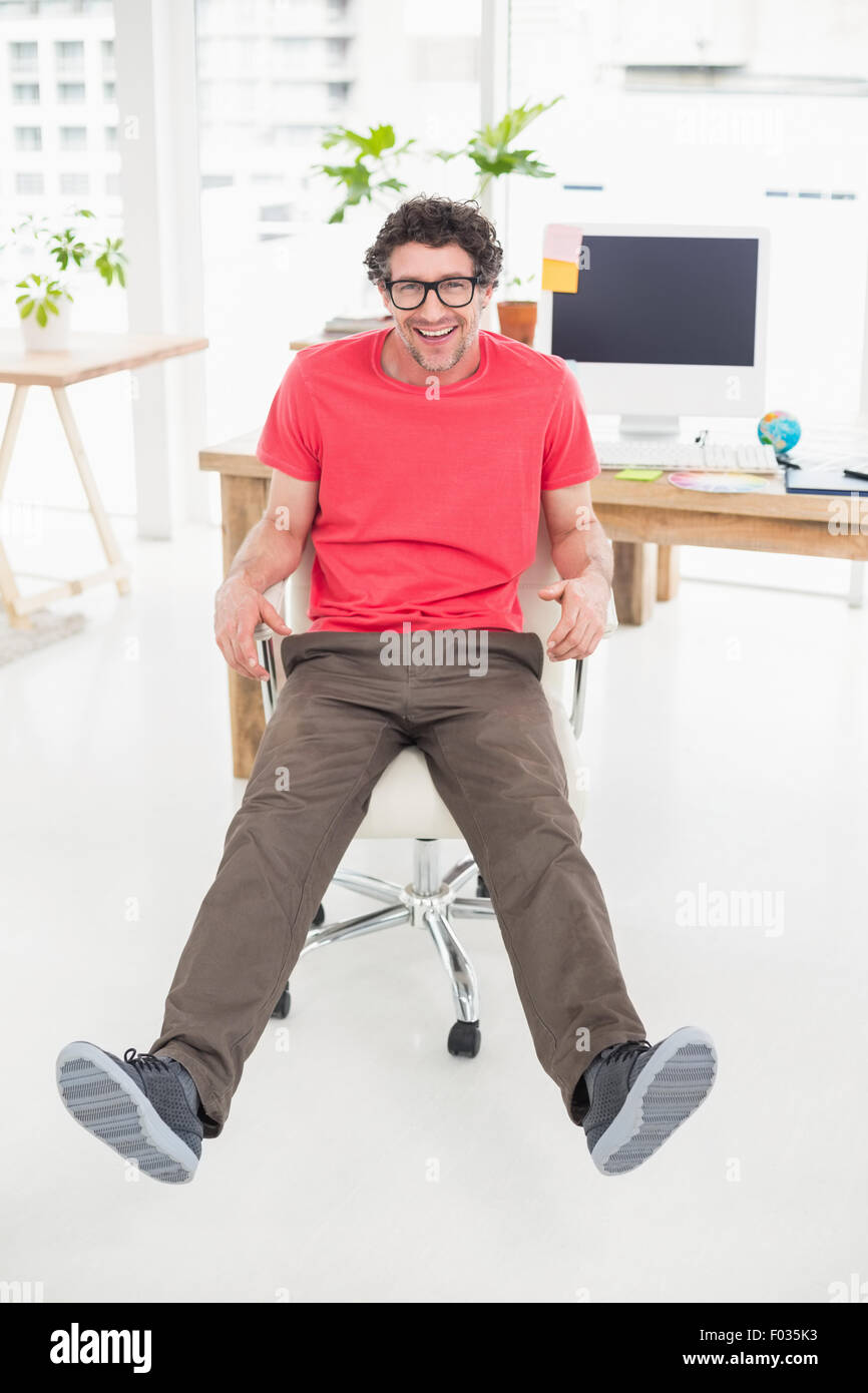 Imprenditore bello seduto su una sedia girevole e usando il suo computer portatile Foto Stock
