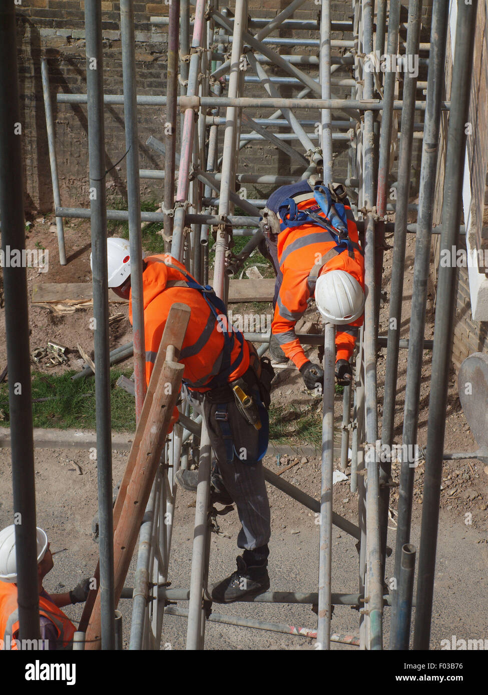 Scaffolders nel processo di smantellamento di una spider web di acciaio su un edificio elencato dopo i lavori di ristrutturazione è stata completata Foto Stock