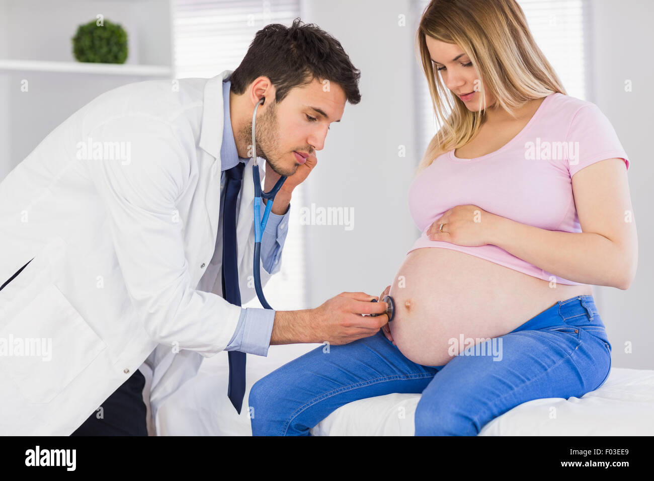 Medico esaminando lo stomaco del paziente in stato di gravidanza Foto Stock