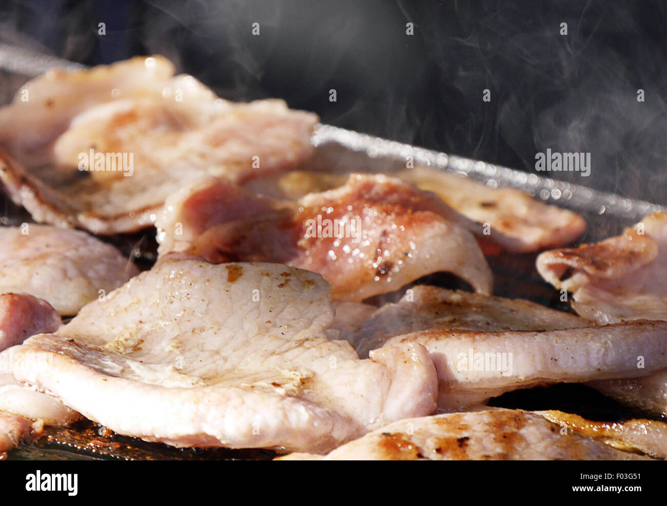 Primo piano della pancetta cottura alla griglia all'aperto Foto Stock