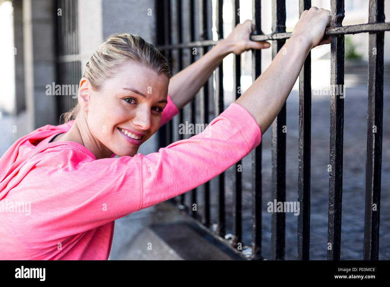 Una bella donna di stretching il suo corpo contro una recinzione Foto Stock