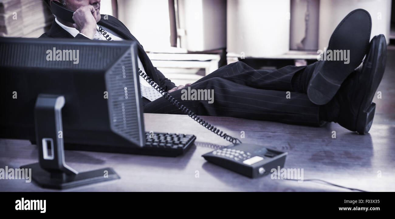 Responsabile di magazzino tramite il telefono alla scrivania Foto Stock