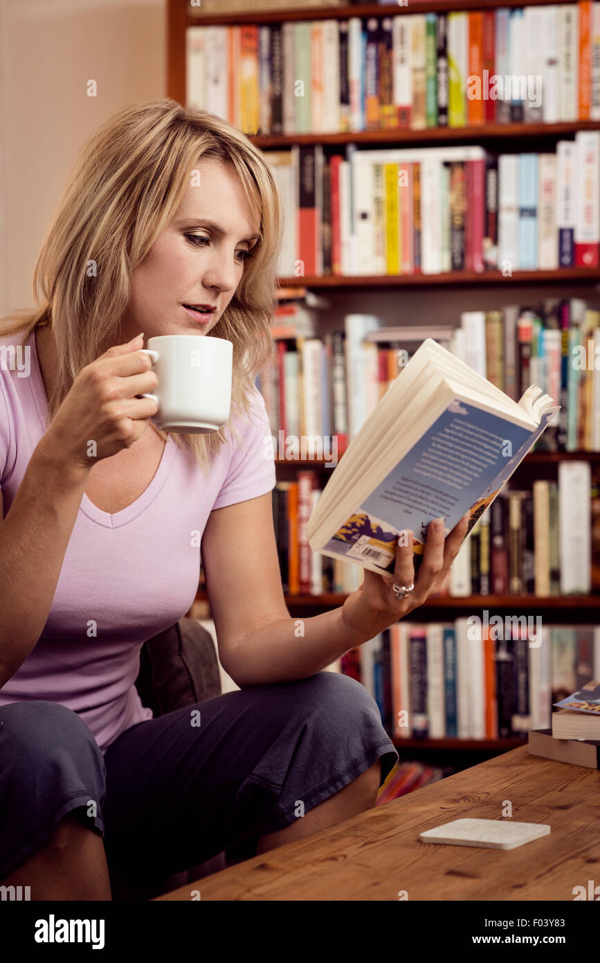 Donna con lettura a home Foto Stock