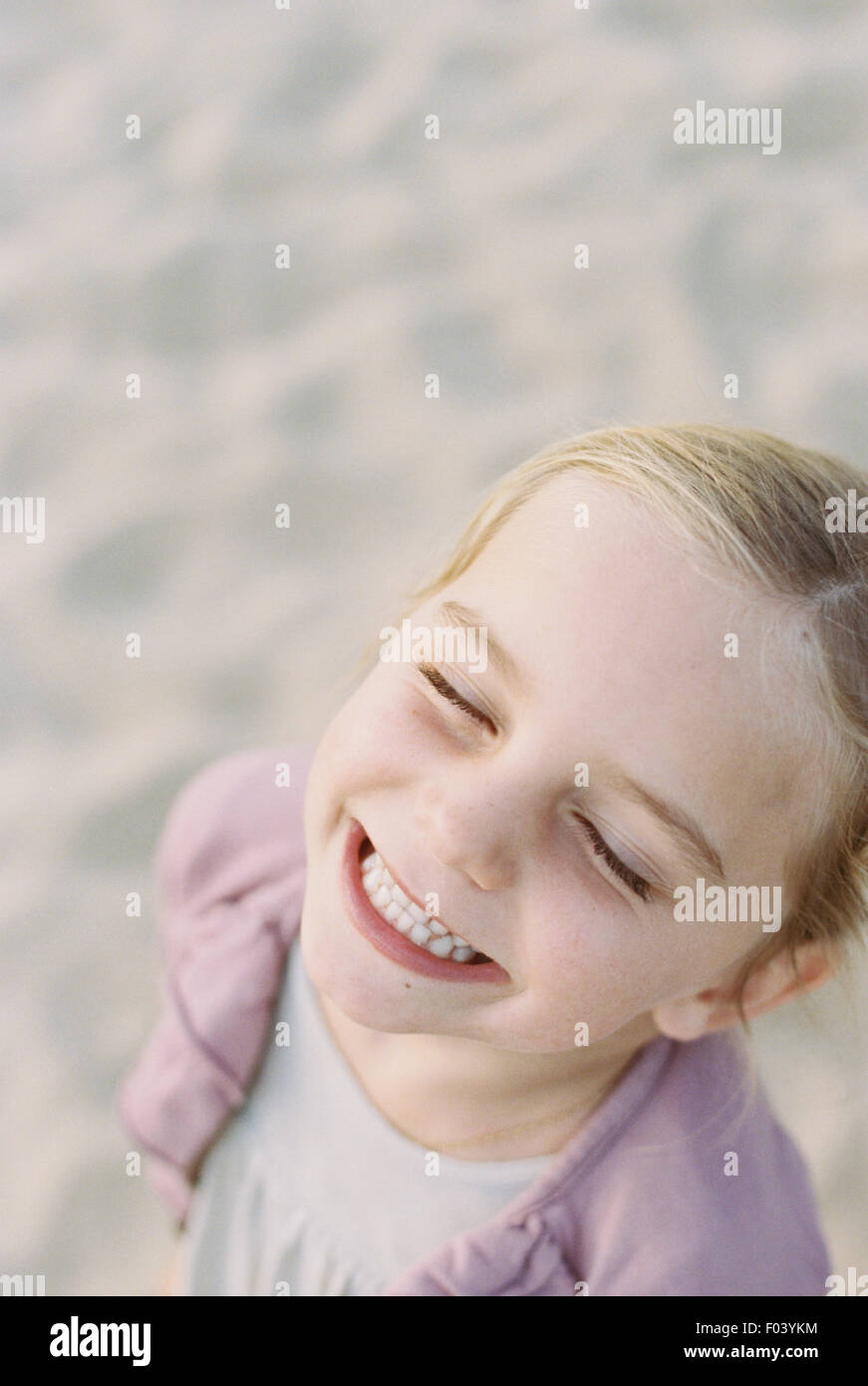 Ritratto di un sorridente ragazza giovane, in piedi su una spiaggia di sabbia. Foto Stock