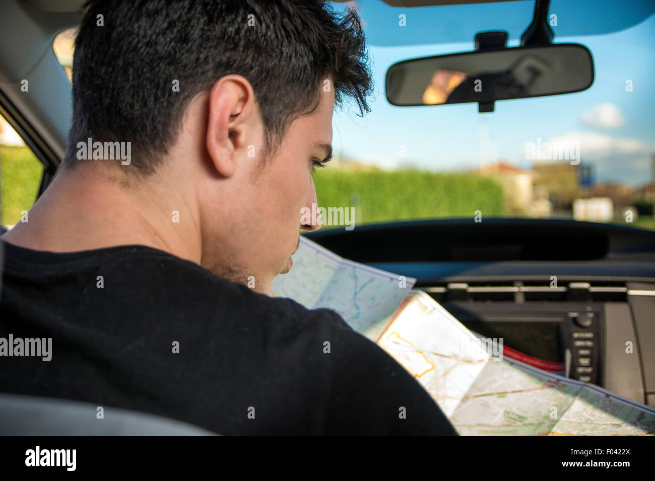 Bel Giovane lettura mappa all'interno di un automobile, cercando le direzioni Foto Stock