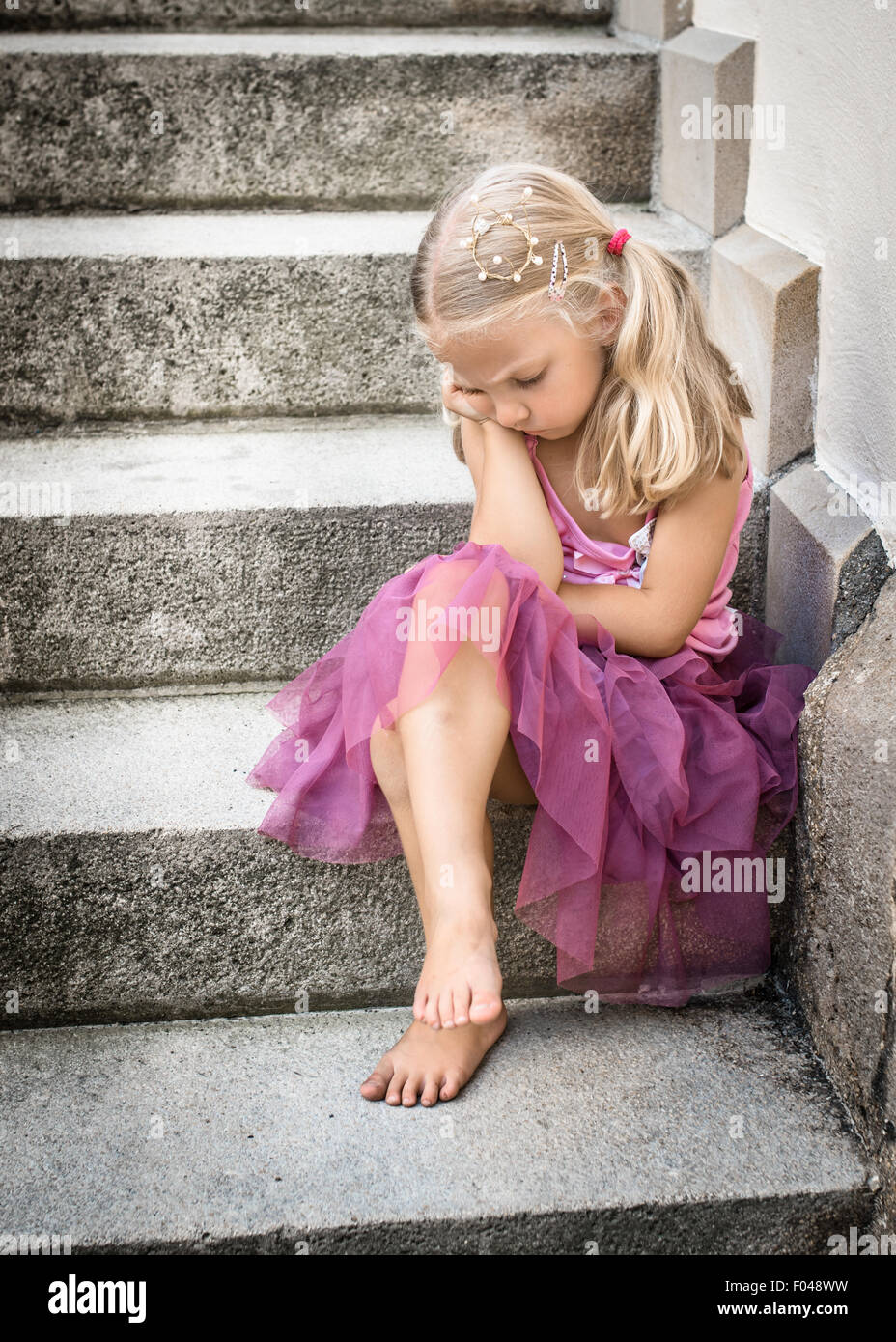 Triste / annoiato / arrabbiato piccola principessa con corona d'oro sul suo capo. Messa a fuoco selettiva. Foto Stock