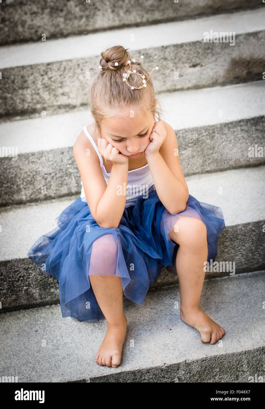 Triste / annoiato / arrabbiato piccola principessa con corona d'oro sul suo capo. Messa a fuoco selettiva. Foto Stock