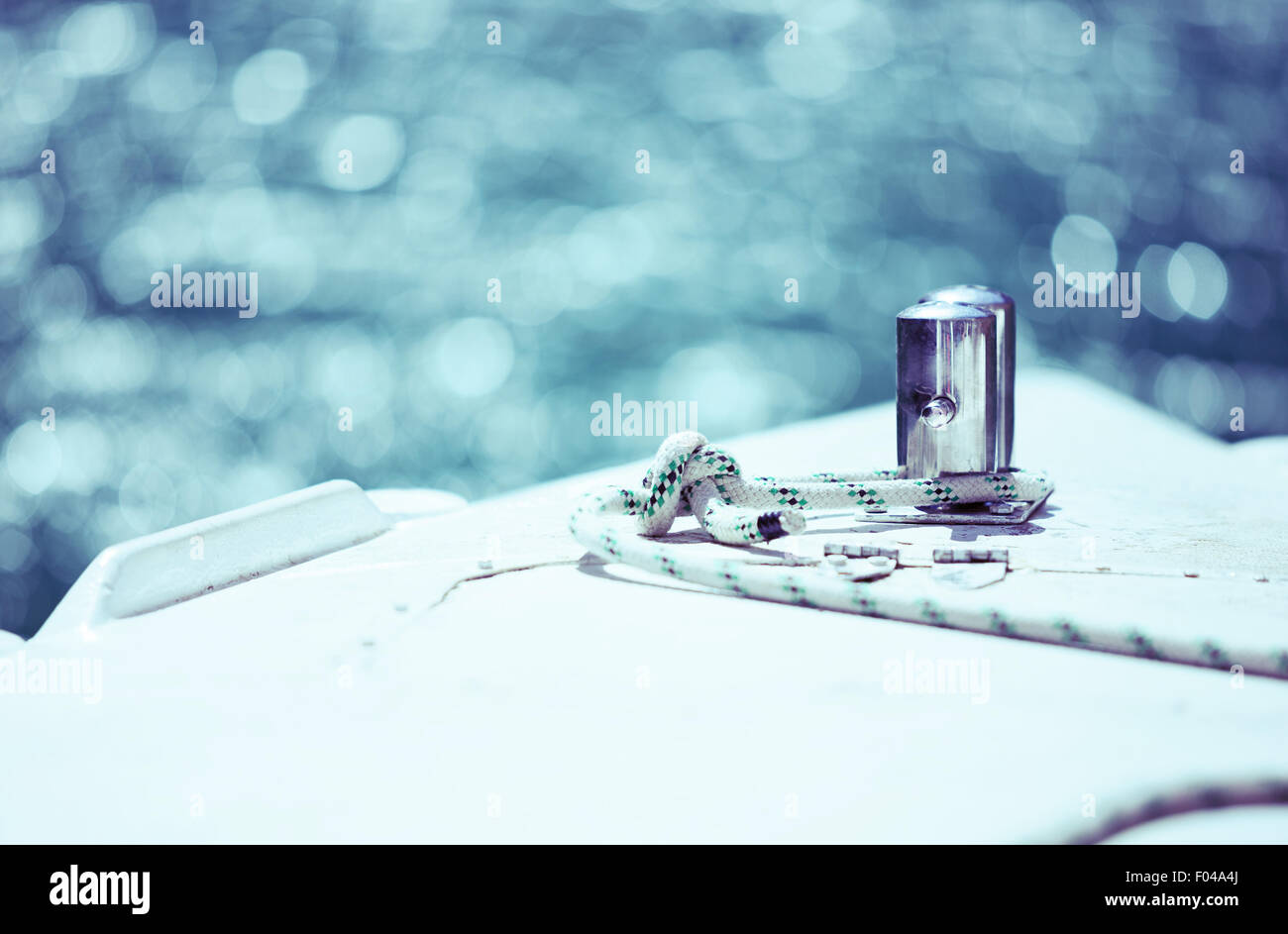 Bianco cima di ormeggio legato attorno al dispositivo di ancoraggio in acciaio sul battello o nave, shallow dof, di colore blu Foto Stock