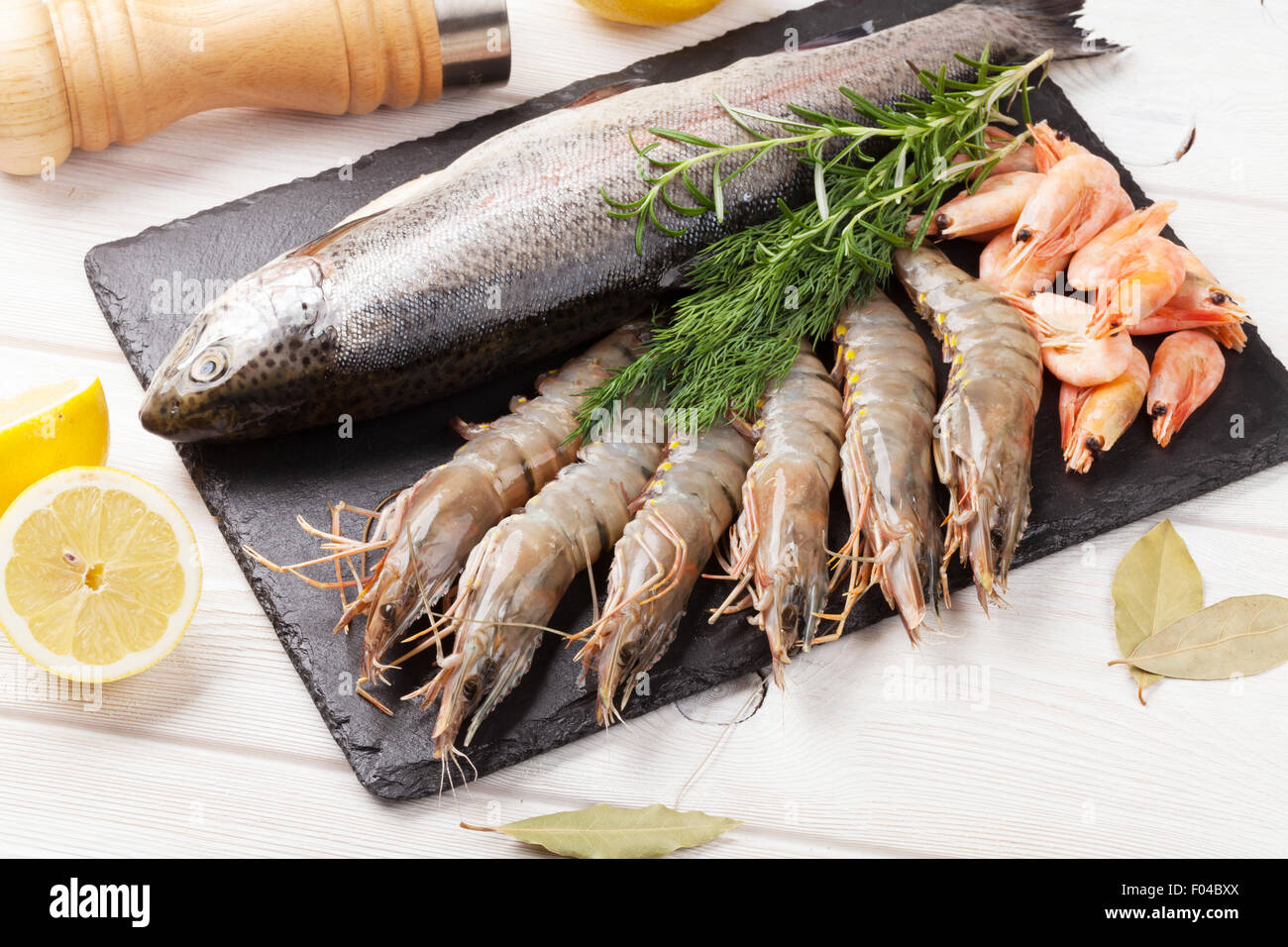 Crudo fresco il cibo del mare con spezie sulla lastra di pietra su un tavolo di legno dello sfondo. Vista superiore Foto Stock