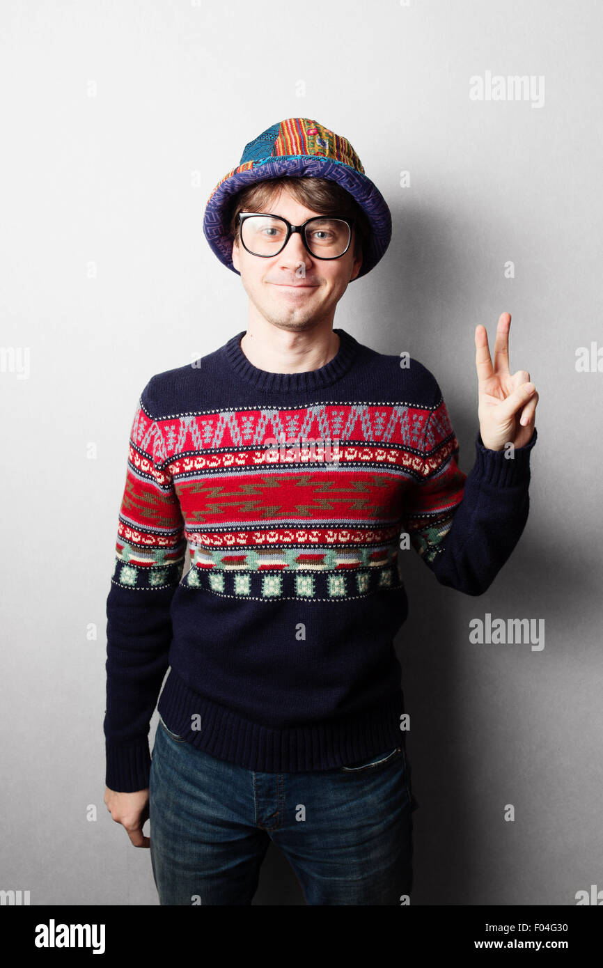 Giovane uomo bello in maglia abiti colorati, muro grigio dietro Foto Stock