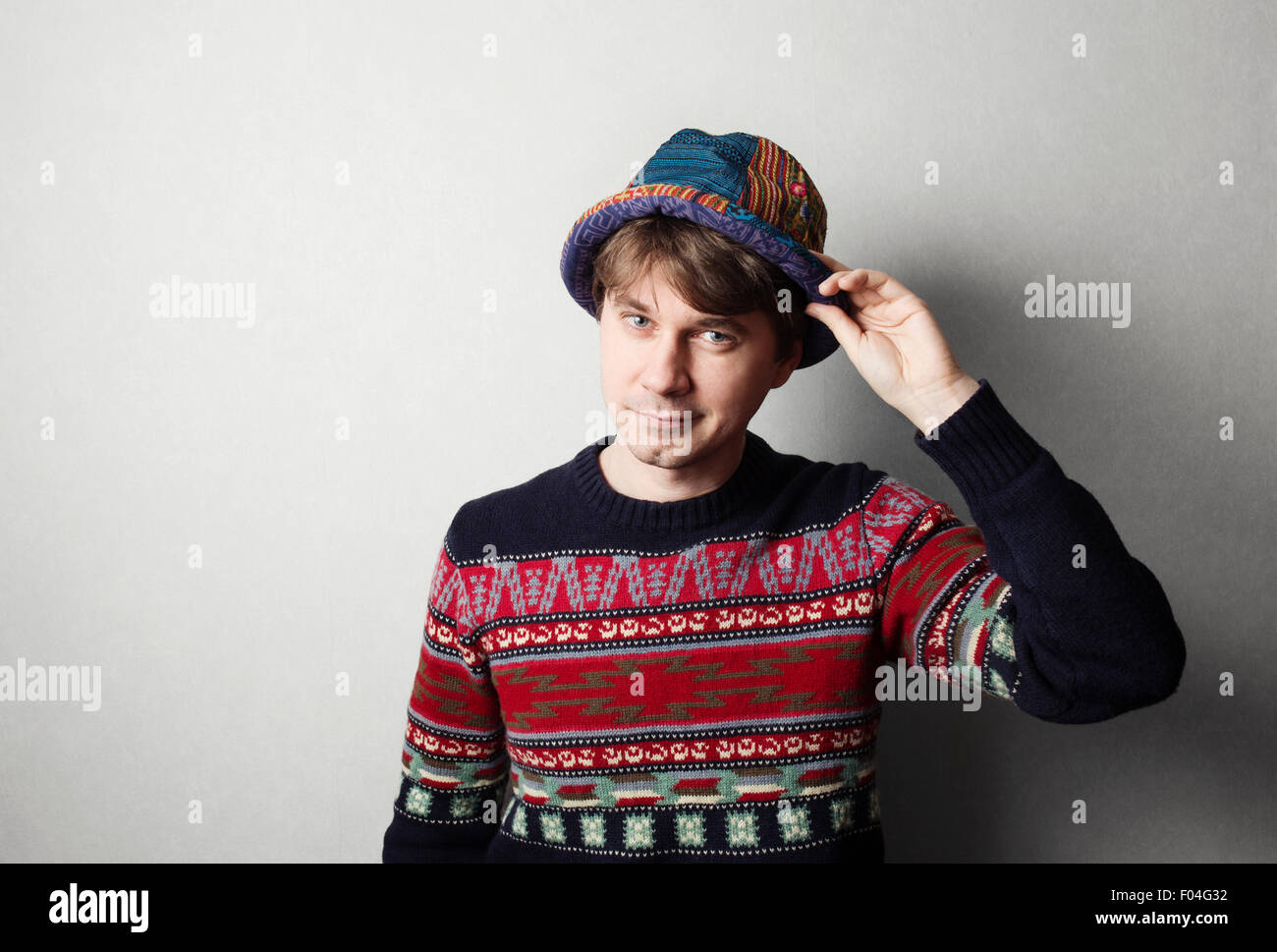 Giovane uomo bello in maglia abiti colorati, muro grigio dietro Foto Stock