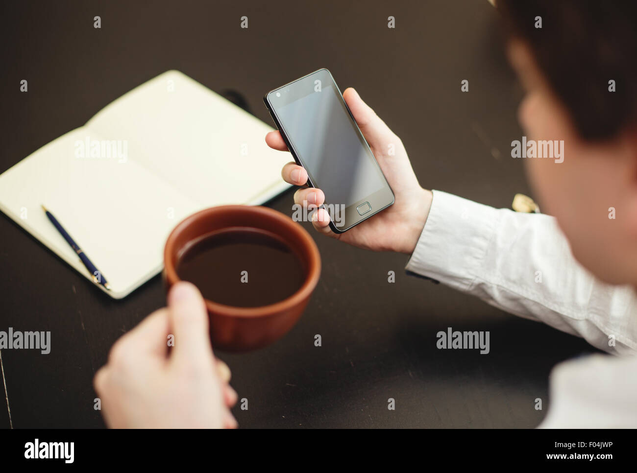L'uomo utilizza lo smartphone, close-up, caffè e pianificazione libro sullo sfondo Foto Stock
