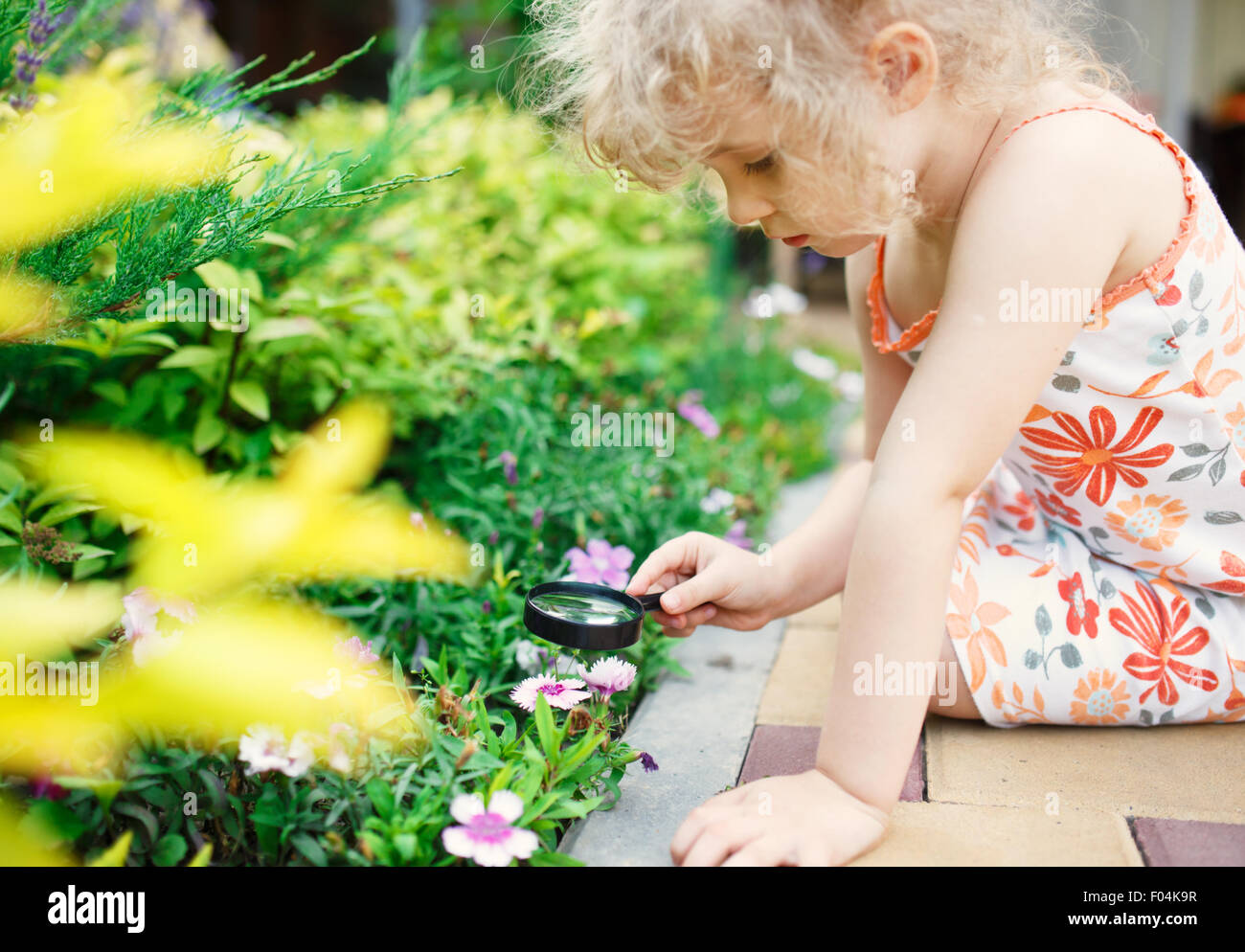 Bambina esplorando la natura con una lente di ingrandimento Foto Stock